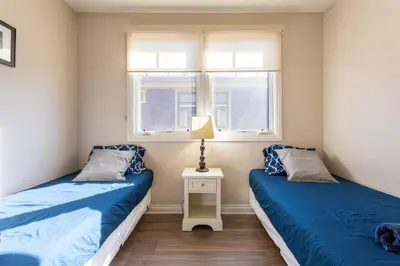 two beds in a room with two windows at Getaway 4BR Home in the Heart of LA in Los Angeles
