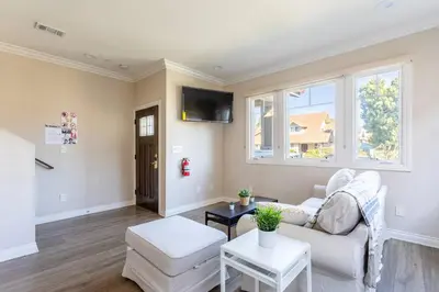 a living room with a white couch and two windows at Getaway 4BR Home in the Heart of LA in Los Angeles