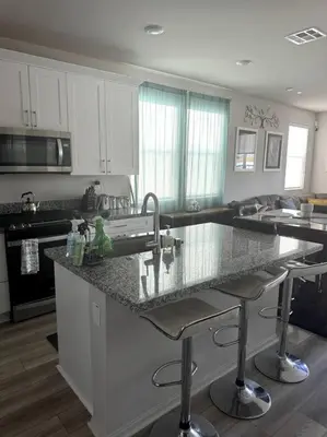 a kitchen with white cabinets and a granite counter top at Cozy Home 20 Mins from DTLA in West Covina