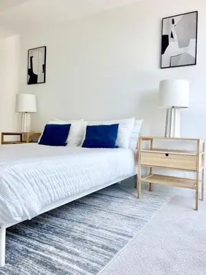 a white bedroom with a large bed with blue pillows at West Hollywood Gem 2-Bedroom Apartment in Los Angeles