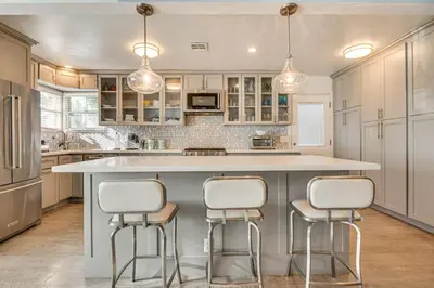 a kitchen with a large island with three bar stools at 4 Mi to Beach Chic Los Angles Home with Patio! in Los Angeles