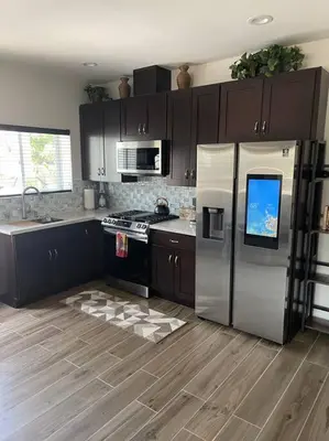 a kitchen with a stainless steel refrigerator and wooden floors at Elegant private studio with private entrance and pool access in San Gabriel