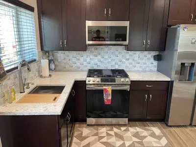 a kitchen with brown cabinets and a stove and a sink at Elegant private studio with private entrance and pool access in San Gabriel