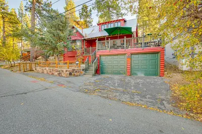 a red house with green garage doors on a street at Hot Tub, Grill and Fire Pit Cabin in Big Bear Lake in Big Bear Lake