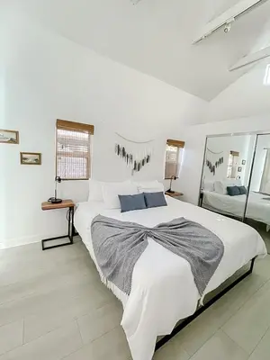 a white bedroom with a large bed and a mirror at Pristine 1BD 1BA Bungalow With Hot Tub in Los Angeles