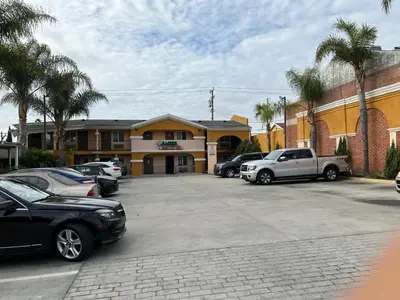 a parking lot with cars parked in front of a building at Amber Motel in Inglewood