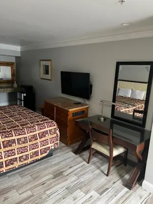 a hotel room with a bed and a desk and a television at Amber Motel in Inglewood