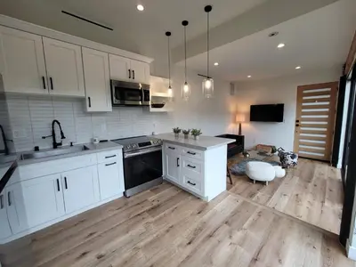 a kitchen with white cabinets and a wooden floor at Sumac in Los Angeles