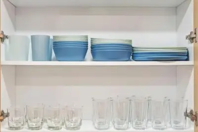 a shelf with plates and glasses on it at Modern Anaheim Stay- Minutes to Disney& Family Fun in Anaheim