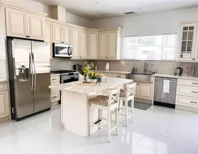 a kitchen with white cabinets and a kitchen island with chairs at Luxury Oasis in Central Encino w Pool & Spa Topeka in Los Angeles