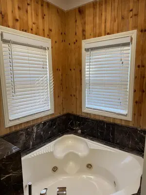 a white tub in a bathroom with two windows at Enjoy Privacy - Pine Mountain - Spacious Home in Pine Mountain Club