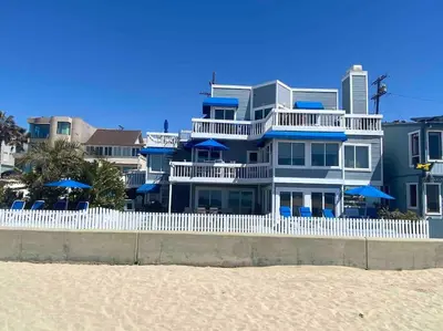 a large blue house with a white fence on the beach at 90210 Beach House Lower Unit in Hermosa Beach