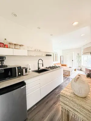 a large kitchen with white cabinets and a sink at Charming Studio Oasis with Pool Near SoFi - MKLAD4 in Los Angeles