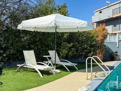 two chairs and an umbrella next to a swimming pool at Charming Studio Oasis with Pool Near SoFi - MKLAD4 in Los Angeles