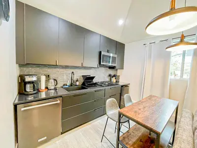 a kitchen with stainless steel appliances and a table at Charming Poolside ADU Near SoFi Stadium - MK3LAD in Los Angeles