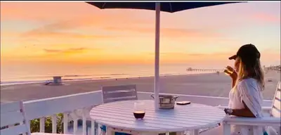 a woman sitting at a table in front of the beach at 90210 Beach House Top Unit in Hermosa Beach