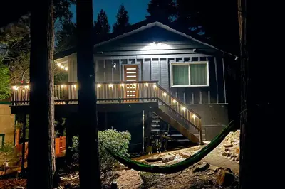 a house with a deck and a hammock in front of it at Beautiful Renovated Cozy Forest Home with Hot Tub in Crestline in Crestline