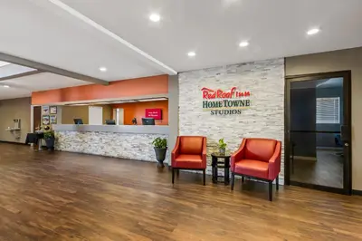 a lobby with two red chairs and a welcome sign at HomeTowne Studios by Red Roof Ridgecrest in Ridgecrest