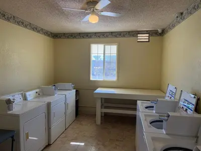 a laundry room with four sinks and a window at HomeTowne Studios by Red Roof Ridgecrest in Ridgecrest