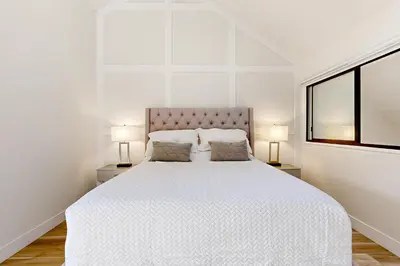 a white bedroom with a large bed with two lamps at Lake Arrowhead Views! Condo with Shared Pool and Spa in Lake Arrowhead