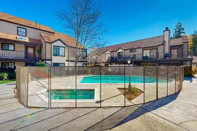 a swimming pool behind a fence in front of a house at Lake Arrowhead Views! Condo with Shared Pool and Spa in Lake Arrowhead