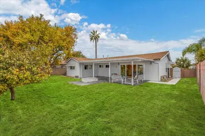 a white house with a yard with a palm tree at Luxurious Newly Remodeled 4 Bedroom Home with Large Backyard near Disneyland in Anaheim