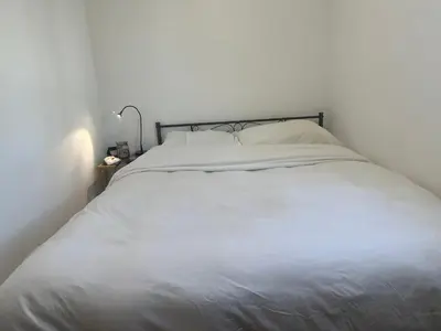 a white bed in a white bedroom with a lamp at Cozy Studio In West Hollywood in Los Angeles