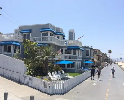 a building on the beach with people walking past it at 90210 Beach House Middle Unit in Hermosa Beach
