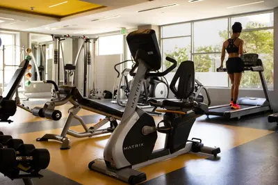 a woman standing in a gym with cardio machines at Urban 1-bedroom Apartment in Los Angeles