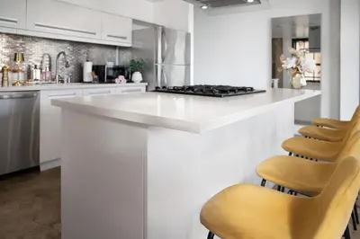 a white kitchen with a white counter and chairs at Urban 1-bedroom Apartment in Los Angeles