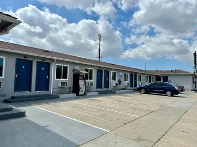 a car parked in front of a building with blue doors at vogue motel in South Gate