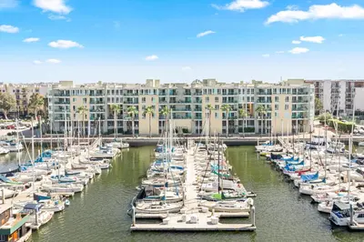 a group of boats docked in a harbor with a building at Coastal Bliss - Luxe 2BR Retreat in MDR - Venice - SM in Los Angeles