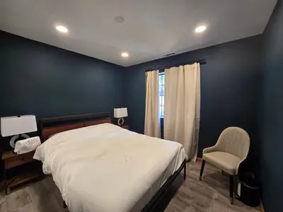 a bedroom with a white bed and a chair at Modern Lagunita Cabin Near the Lake in Big Bear Lake