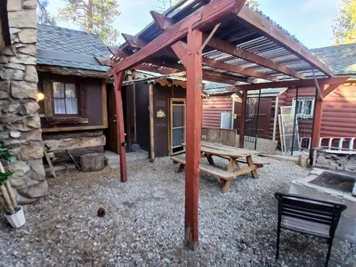 a wooden pergola over a picnic table in front of a cabin at Cabin 33, 3 bedroom 2 bath in Big Bear Lake