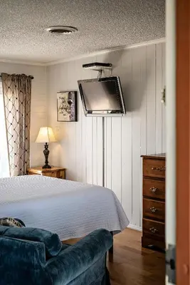 a bedroom with a bed and a tv on the wall at Hilltop Tavern and Inn in Apple Valley