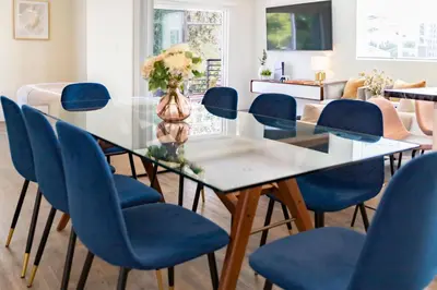 a dining room with a glass table and blue chairs at 5 Star Private House 5 rooms in Los Angeles