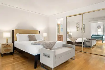 a bedroom with a bed and a chair and a mirror at Adorable 4 bedroom home with Pool & more in Los Angeles