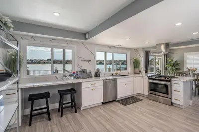 a large kitchen with white cabinets and windows at The Lakefront Oasis in Victorville