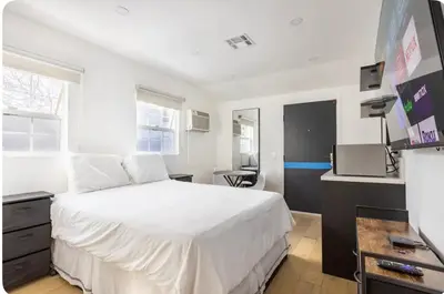 a bedroom with a large white bed and a desk at Charming one bed one bath privet studio in Tarzana