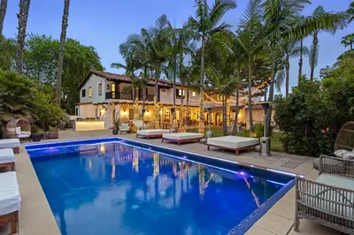 a swimming pool in front of a house with palm trees at Mediterranean Dream Villa Oasis in Los Angeles