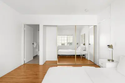 a bedroom with a white bed and a mirror at Modern Furnished 2 Bedroom in West LA in Los Angeles
