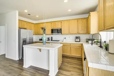 a kitchen with wooden cabinets and a vase on a counter at Pool Table and Charcoal Grill Home in Victorville! in Victorville