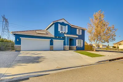 a blue house with a garage on a street at Pool Table and Charcoal Grill Home in Victorville! in Victorville