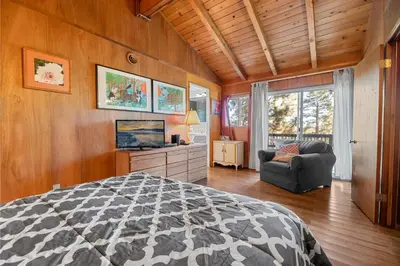 a bedroom with a bed and a chair and a window at Casita de Sergio - Peek-A-Boo Lake View, Walk to Lake, Fireplace in Big Bear Lake