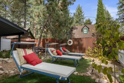 a yard with two lounge chairs and a fence at Casita de Sergio - Peek-A-Boo Lake View, Walk to Lake, Fireplace in Big Bear Lake
