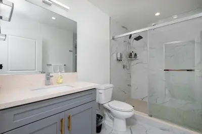 a white bathroom with a toilet and a shower at Stunning 3-BR Residence with Free Parking & Patio in Los Angeles