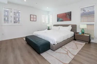 a white bedroom with a large bed and a green ottoman at Luxury 2BR Stay Balcony Views and Free Parking in Los Angeles