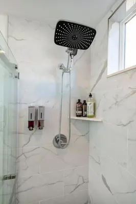 a shower in a bathroom with white marble walls at Experience Lavish LA Living Sleek 2BR with Parking in Los Angeles