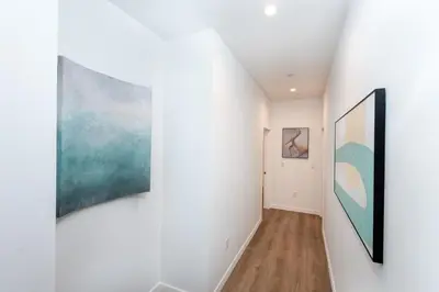 a hallway with white walls and paintings on the walls at Ultimate Luxurious Penthouse with Private Balcony in Los Angeles