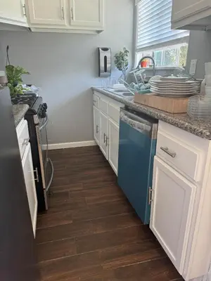 a kitchen with white cabinets and a blue dishwasher at Hollywood escape in Los Angeles